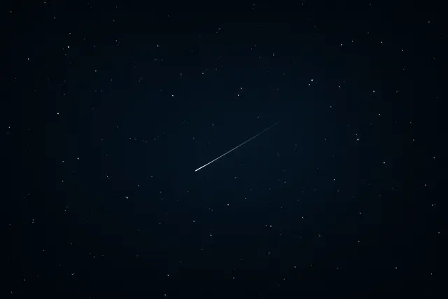 Wide dark starfield with a single faint streaked point of light among sharp stars