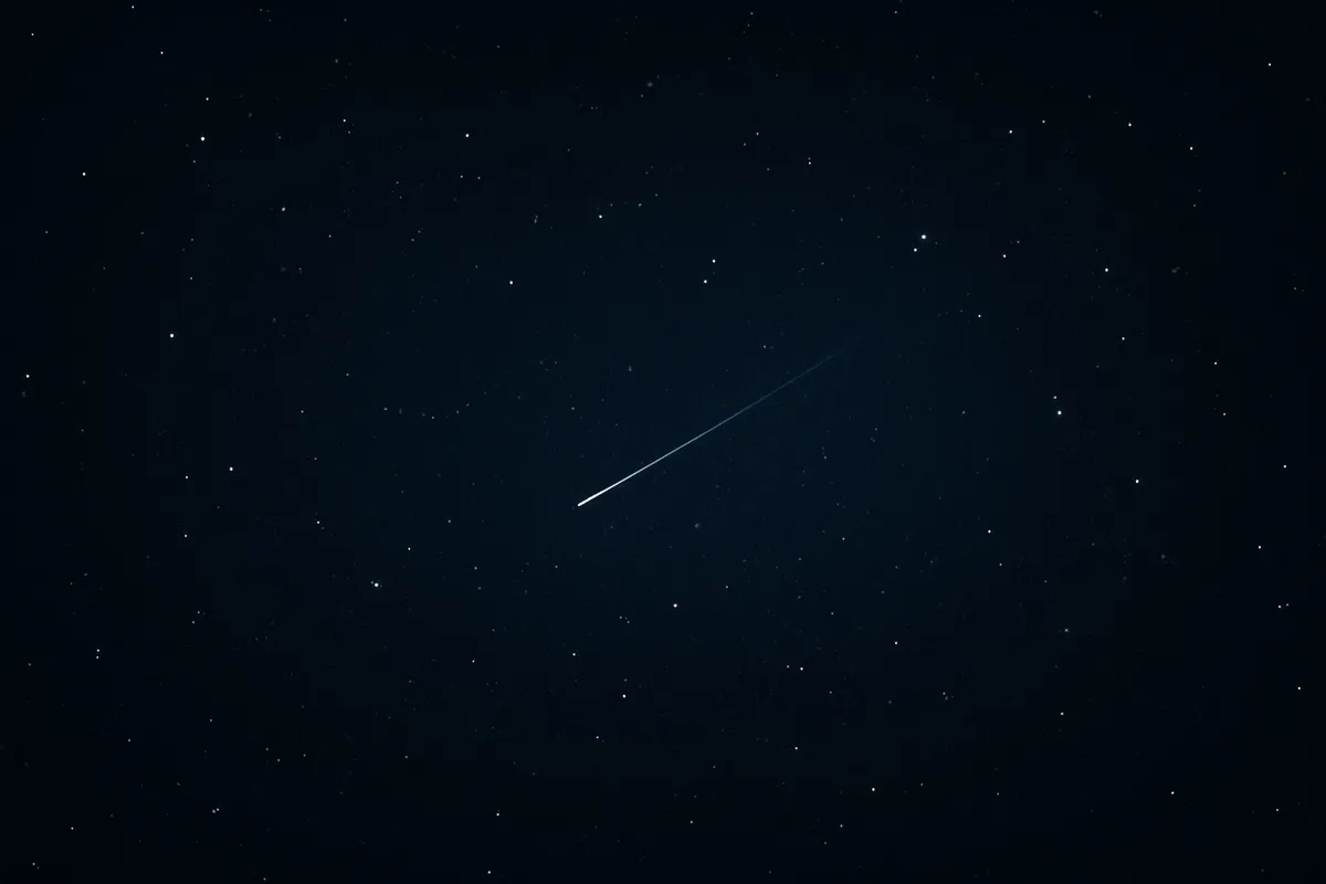 Wide dark starfield with a single faint streaked point of light among sharp stars