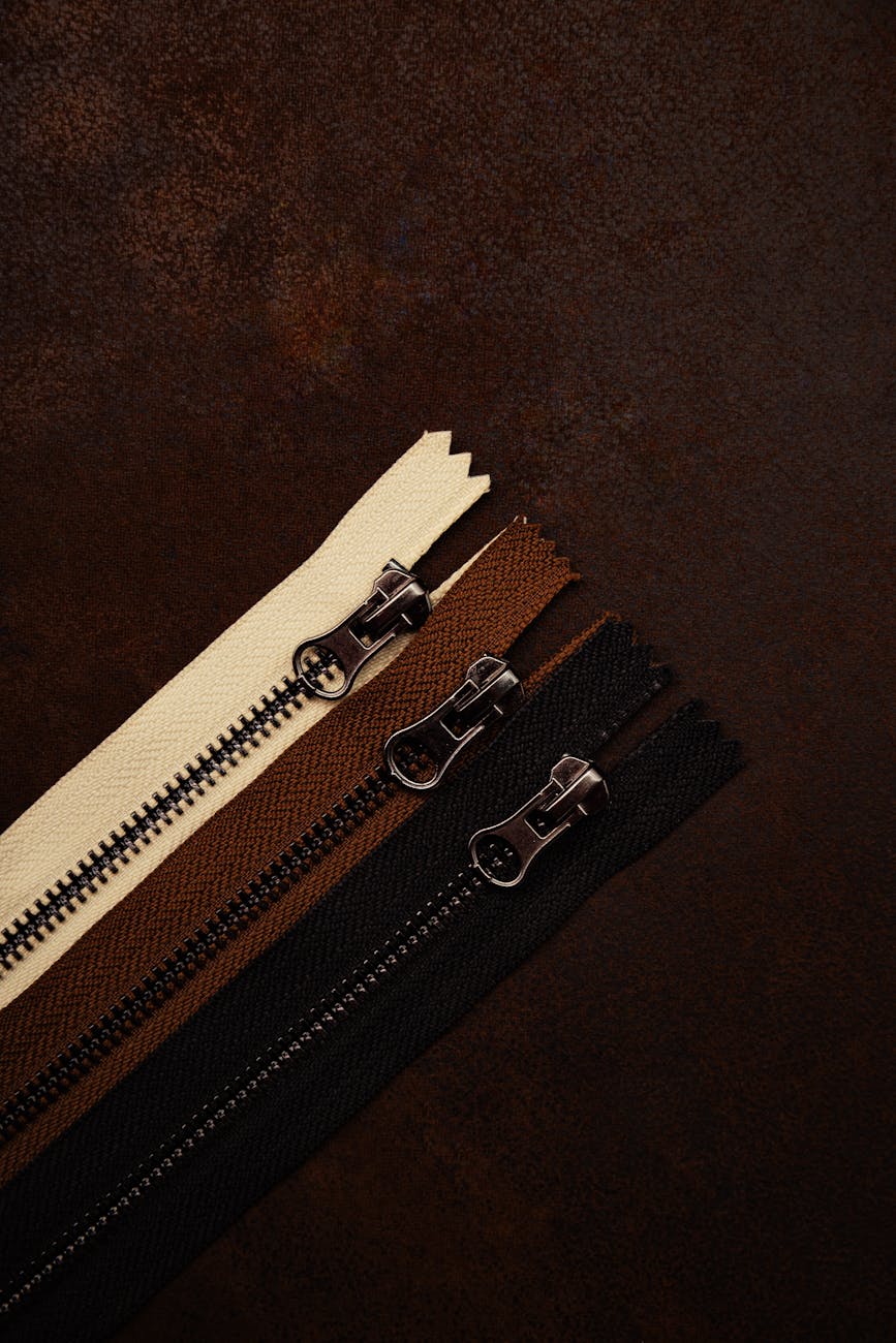 close up of assorted zippers on dark fabric