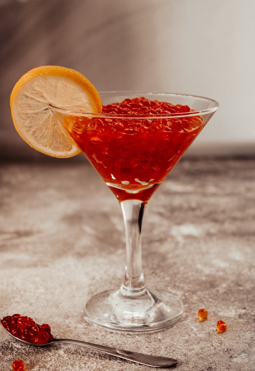 red salmon eggs in clear drinking glass with sliced lemon