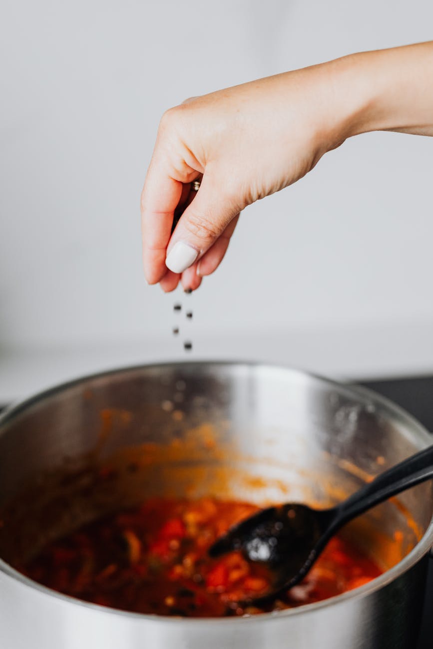photo of a person putting black pepper into a pot