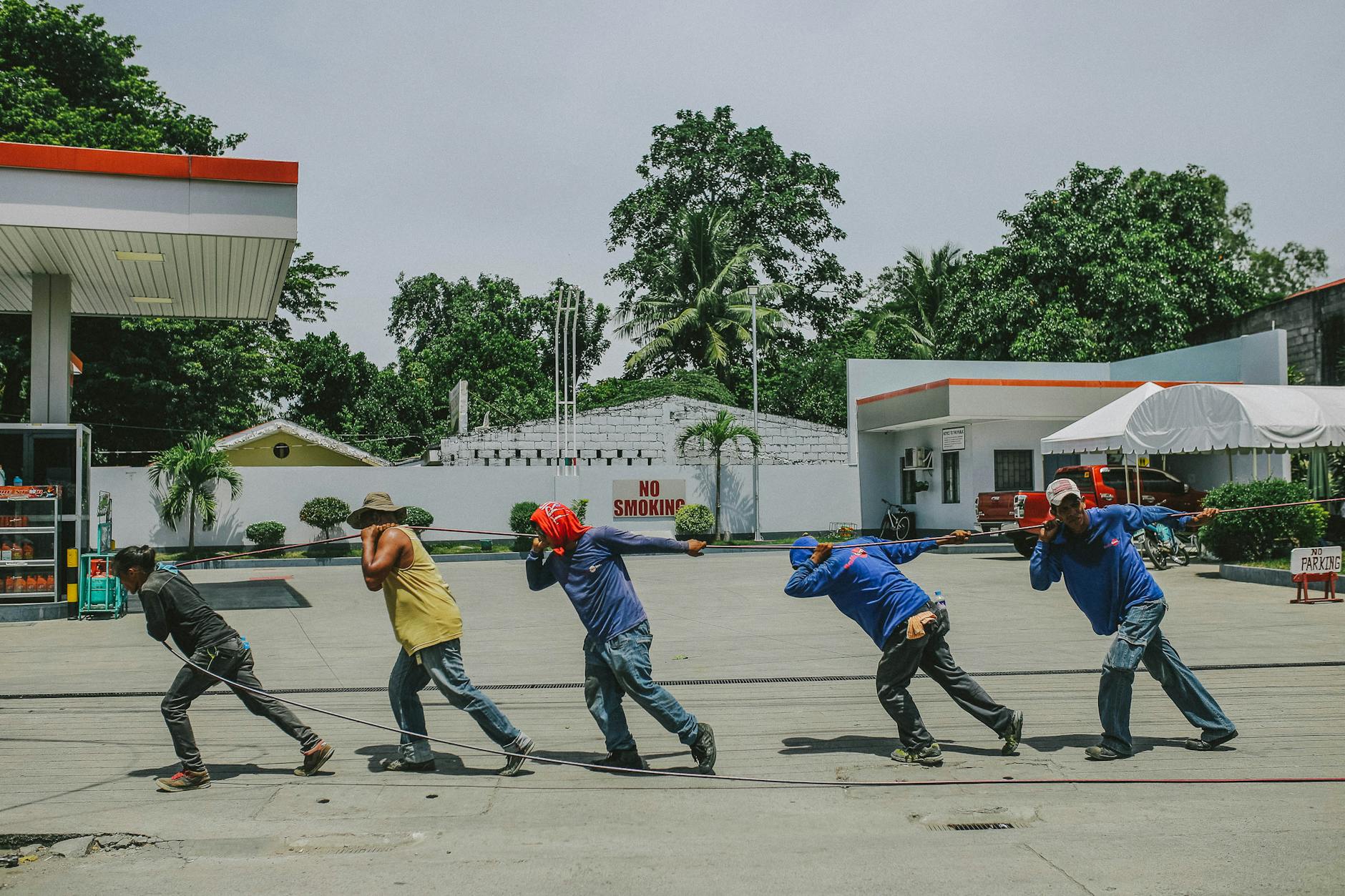 five men pulling black rope