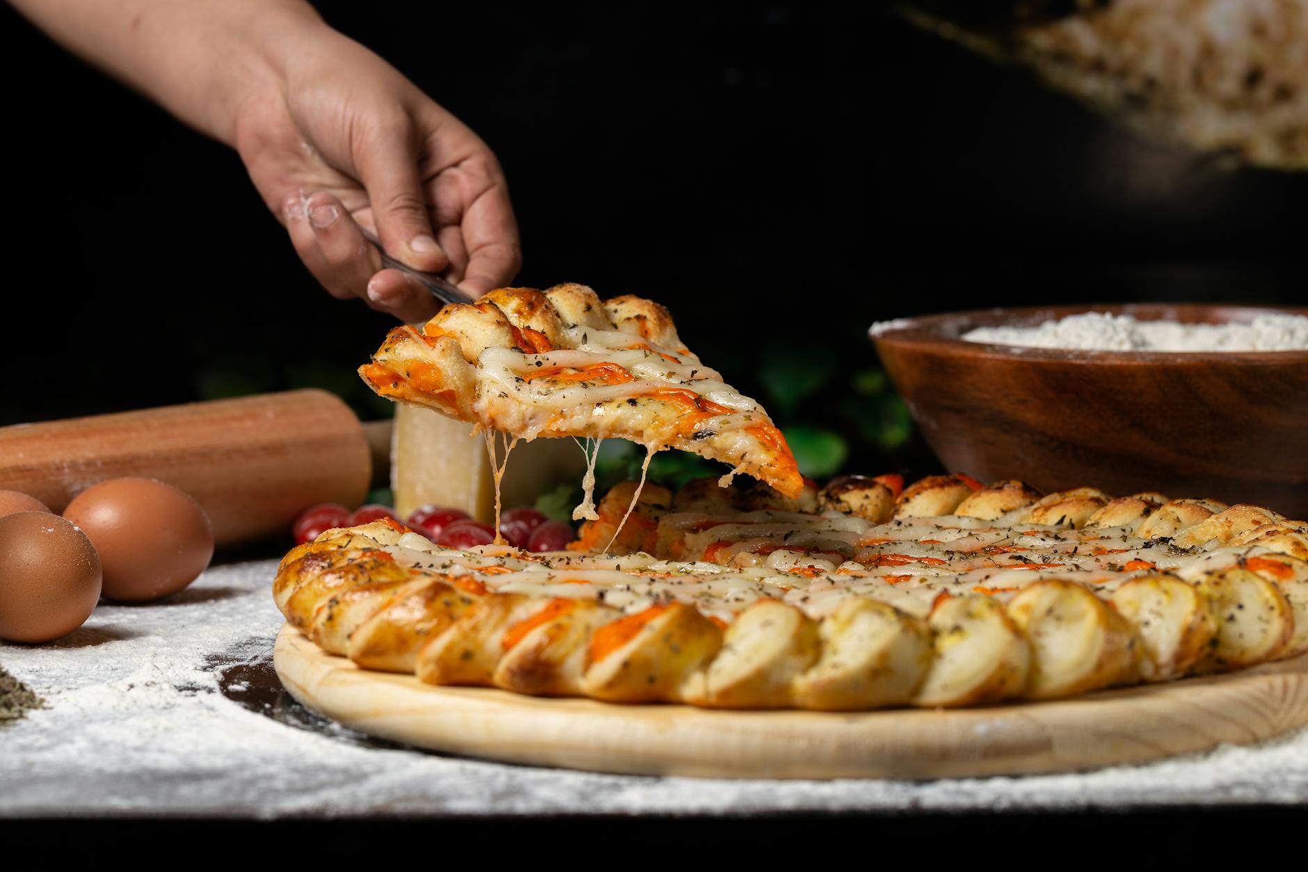person holding pizza on wooden board